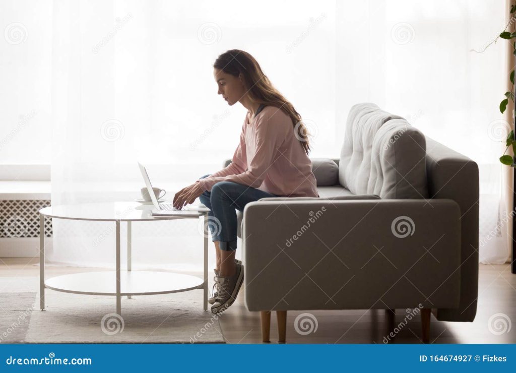 Сосредоточенная молодая женщина, работающая на ноутбуке в гостиной Стоковое  Изображение - изображение насчитывающей интернет, кресло: 164674927